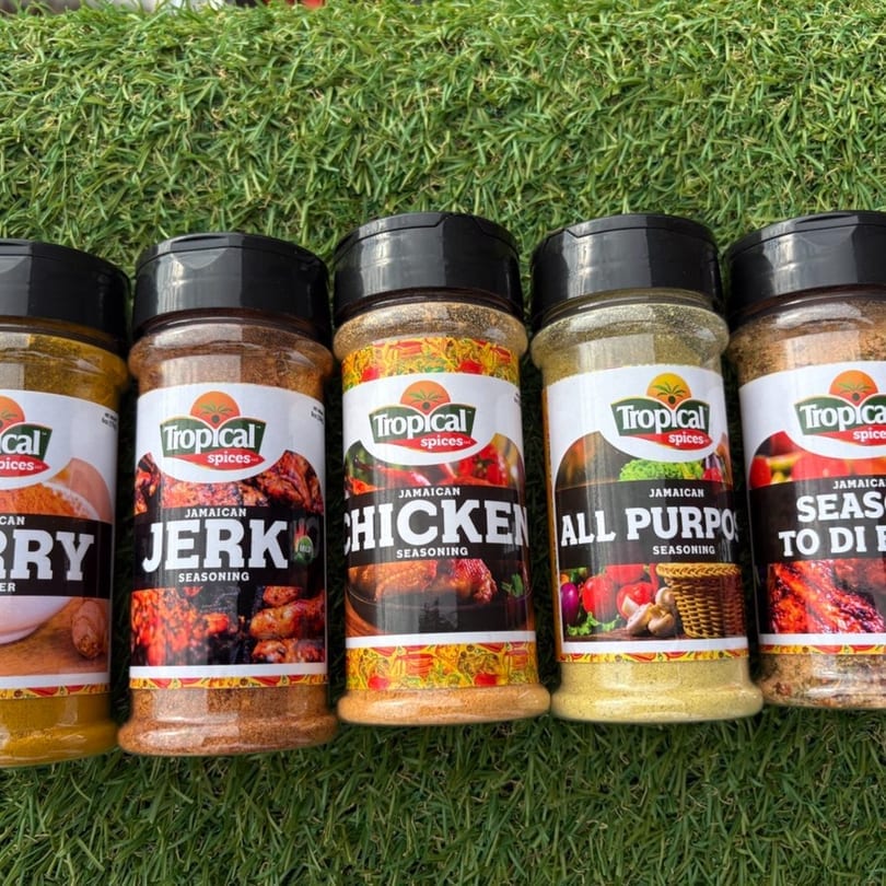Five Tropical Spices Jamaican seasoning bottles, including Curry, Jerk, Chicken, All Purpose, and Season to Di.
