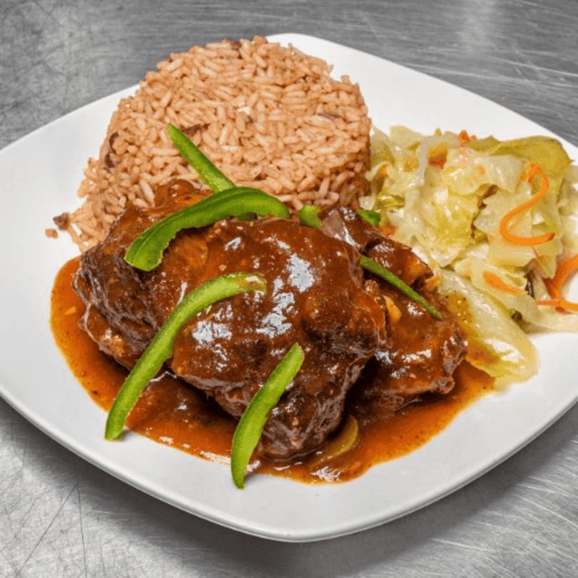 Oxtail stew with rice and peas, and steamed cabbage on a white plate.